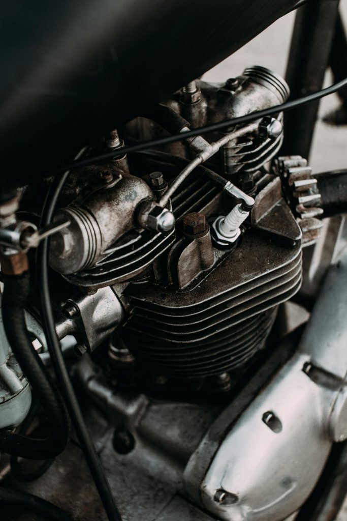 Part of motorbike with engine and metal details on asphalt road of city
